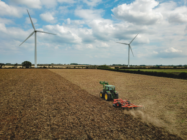 tractor in field with wind turbines