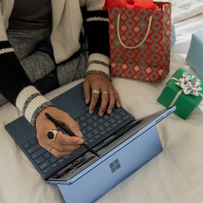 person online shopping next to gifts