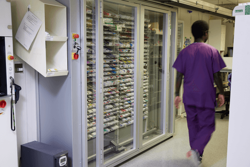 Pharmacist walking past a hospital pharmacy robot