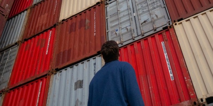 man staring at shipping containers 